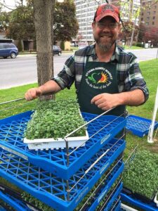 Mike's Garden Harvest- Photo of Mike with vegetable sprouts at the farmer's market